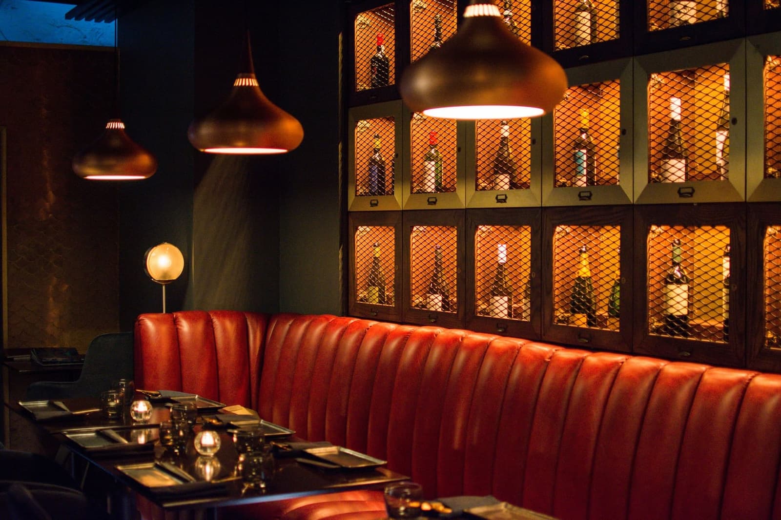 Salvatore's main dining room — warm wood, marble tables, soft pendant lighting and floor-to-ceiling windows on Pacific Highway in downtown San Diego