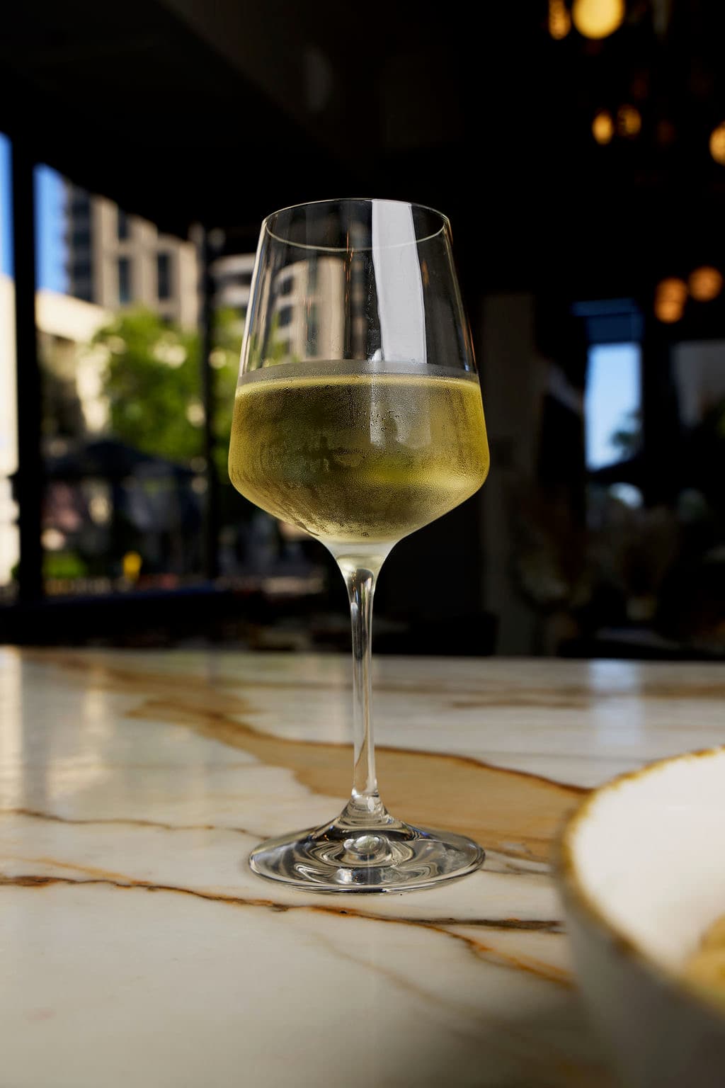 A glass of white wine on the marble bar in the lounge at Salvatore's, a short walk from the Manchester Grand Hyatt